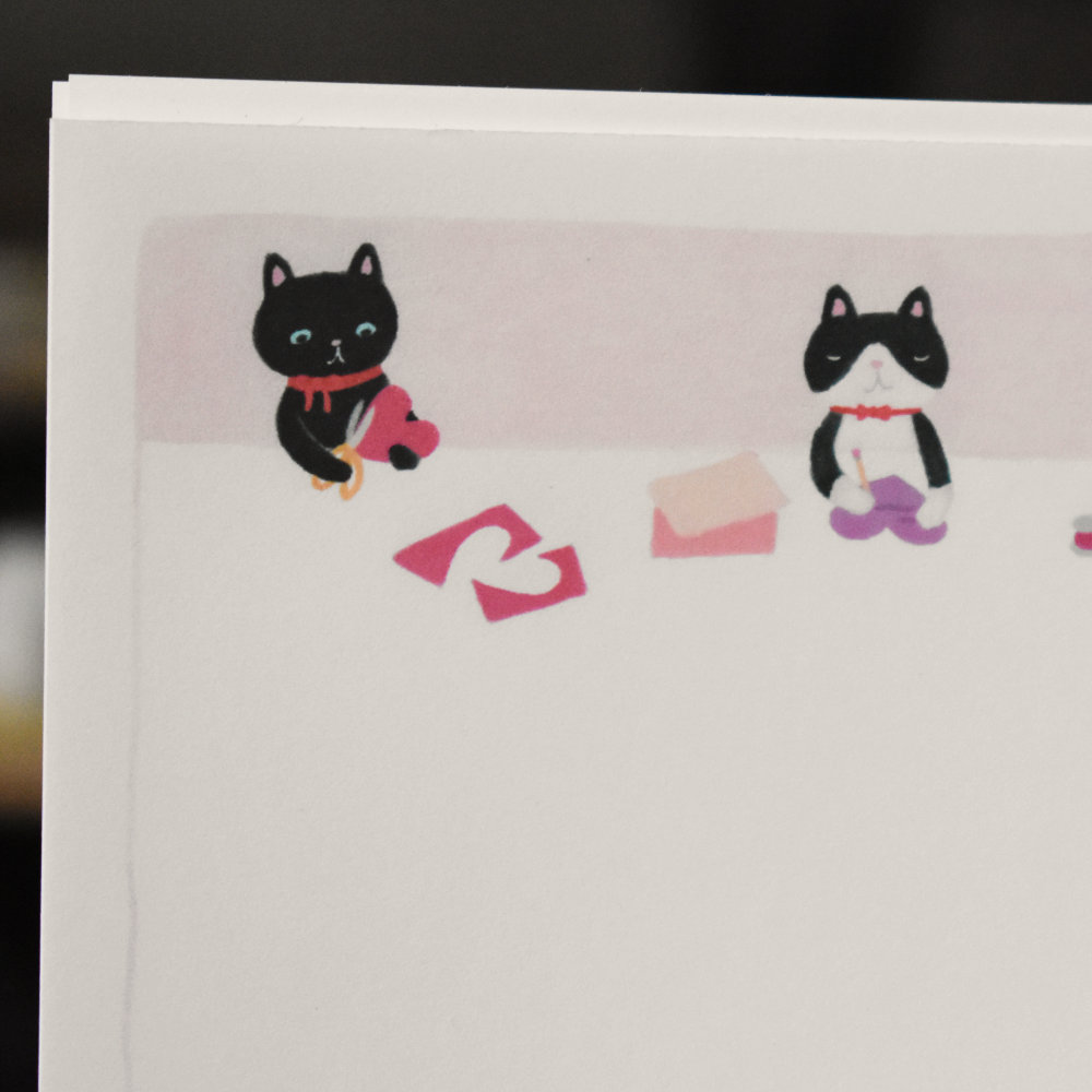 Closeup of stationery featuring cats making Valentines