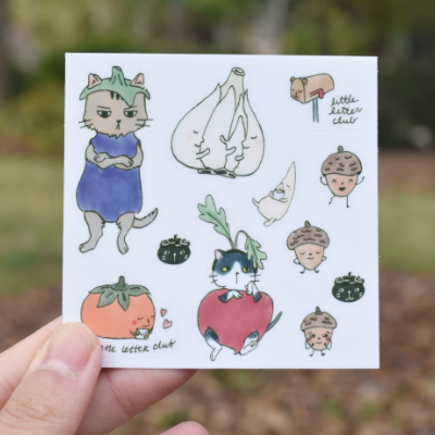 Closeup of stickers featuring cats in veggie costumes and other cute characters